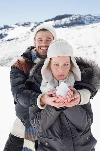 Pareja con nieve en manos sobre el paisaje nevado