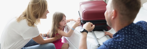 Una pareja con una niña en un hotel cierra un primer plano de maleta