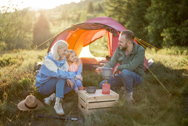 Pareja con niña tiene picnic en el camping en las montañas