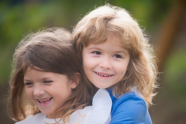 Pareja de niños abrazándose y besándose Niños encantadores al aire libre Niños felices divirtiéndose al aire libre Niños jugando en el parque de primavera