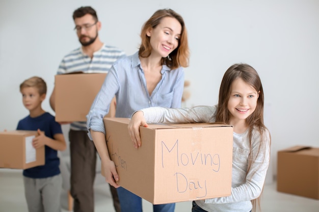 Pareja con niños cargando cajas en el interior Familia feliz el día de la mudanza