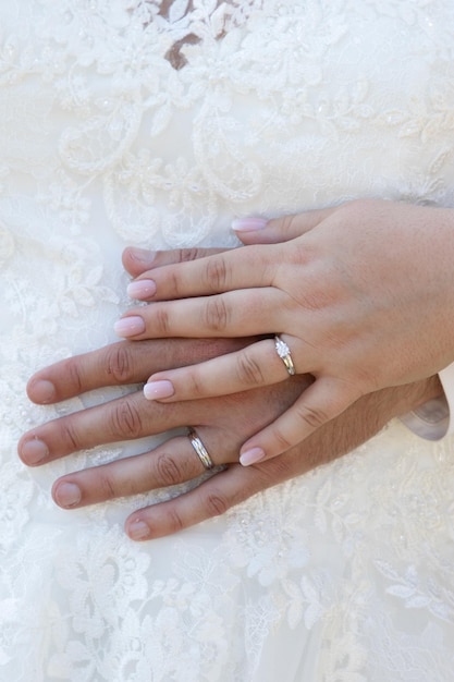 pareja de novios anillos dedos novia y el novio manos en matrimonio descansando sobre vestido blanco