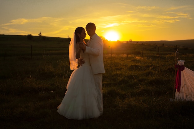 Pareja de novios está bailando en la puesta de sol