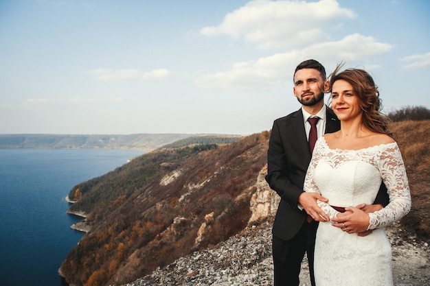 Pareja de novios la novia y el novio tomados de la mano sobre un fondo de montañas y ríos