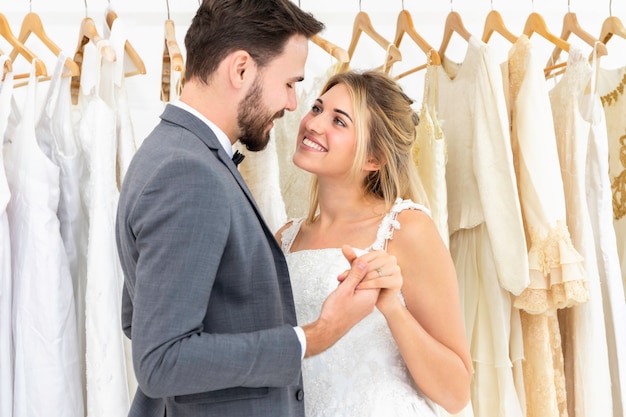 Pareja de novios de raza caucásica bailando y bromeando en estudio de boda.