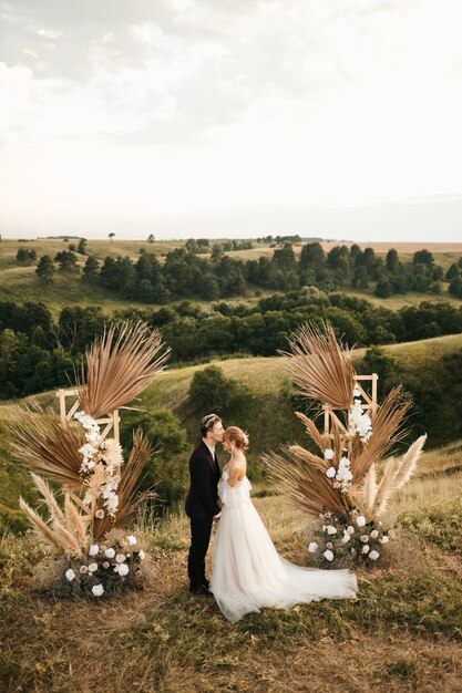 Foto pareja de novios recién casados se besan después de la ceremonia en el arco