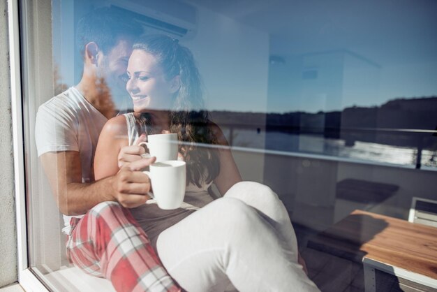 Foto pareja o matrimonio en su nueva casa mirando por la ventana