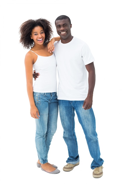 Pareja ocasional en jeans y tops blancos sonriendo a la cámara