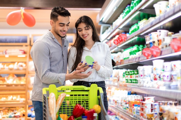 Una pareja de Oriente Medio en la compra de comestibles sosteniendo un frasco en un supermercado