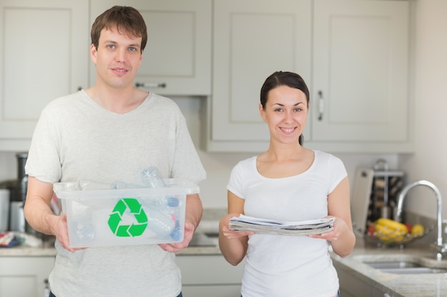 Pareja con papelera de reciclaje y periódicos