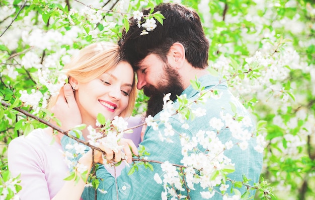 Foto pareja pasa tiempo en el jardín de árboles en flor de primavera pareja riendo y abrazándose feliz día de pascua