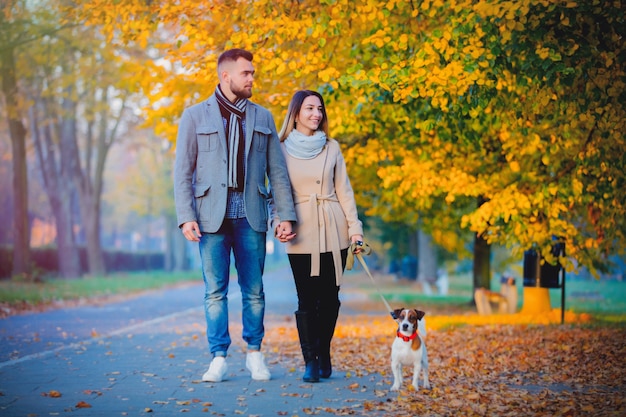 Pareja con perro en el callejón de la temporada de otoño.