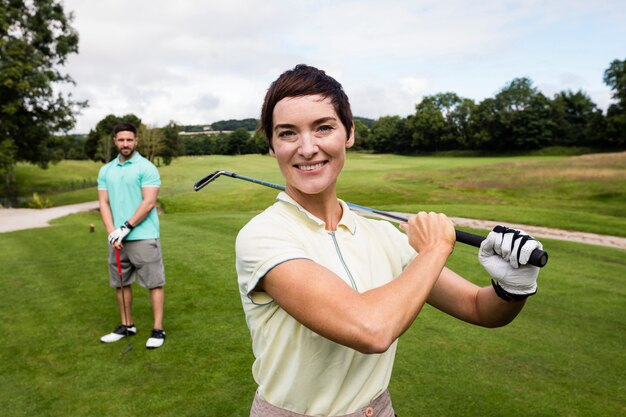 Pareja de pie con el club de golf en el campo de golf