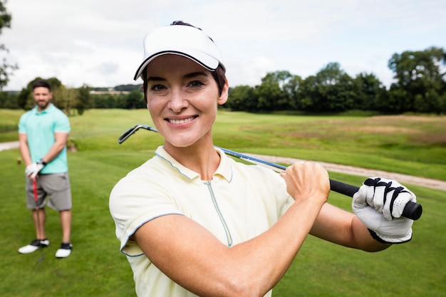 Pareja de pie con el club de golf en el campo de golf