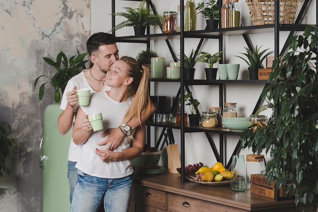 Foto pareja de pie en la cocina amándose