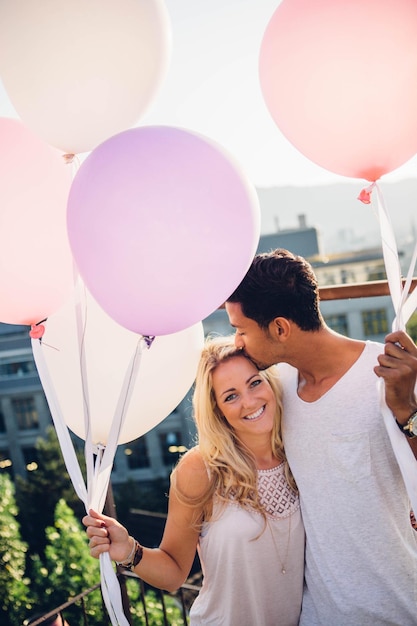 Una pareja de pie con globos contra el cielo