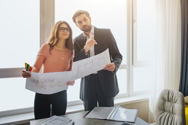 Pareja de pie en la habitación y sosteniendo el plano