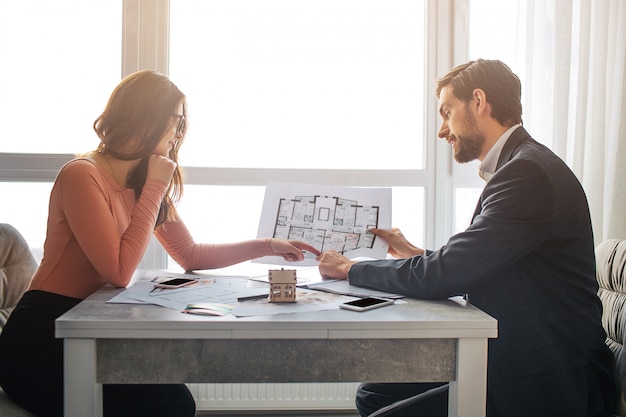 Pareja de pie en la habitación y sosteniendo el plano