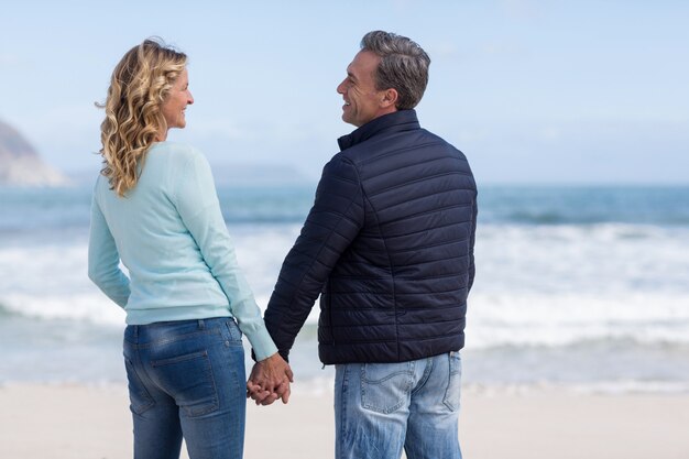 Pareja de pie con las manos en la playa