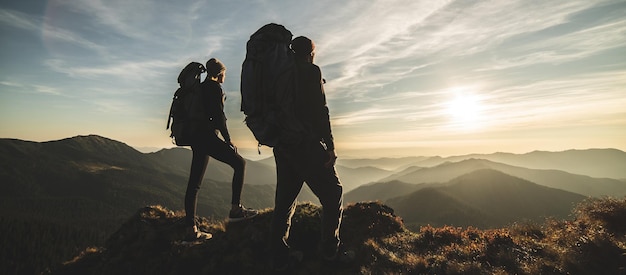 La pareja de pie en la montaña con un pintoresco fondo de puesta de sol