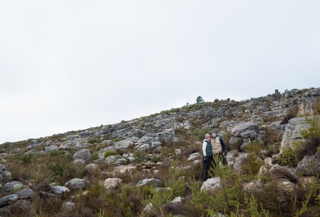 Pareja de pie en el paisaje rocoso contra el cielo claro