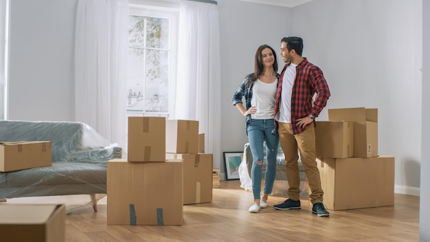 Una pareja de pie en un salón con cajas apiladas en el suelo.