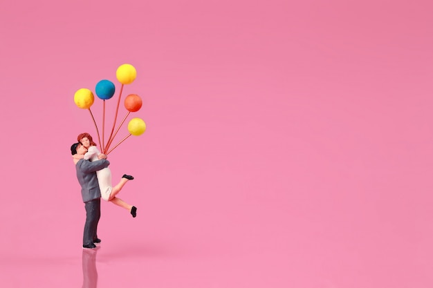 Una pareja de pie y sosteniendo globo en rosa