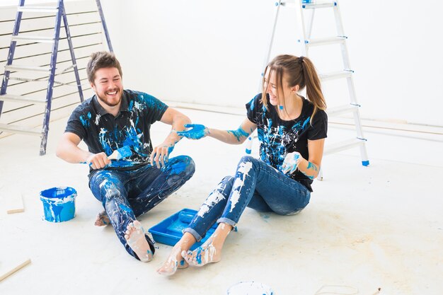 Pareja va a pintar la pared, están mezclando el color y divirtiéndose