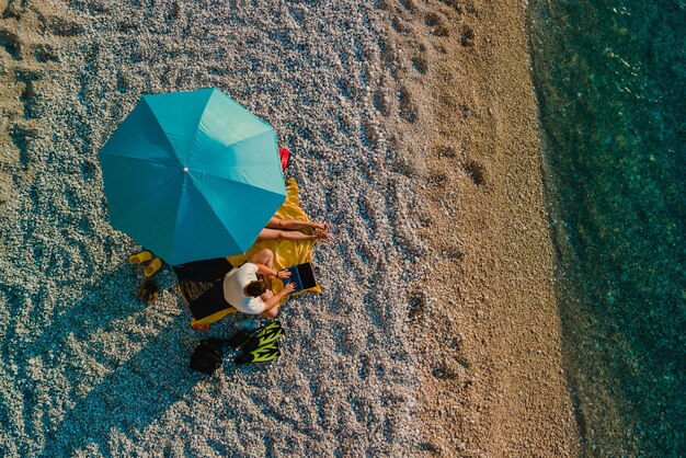 Pareja en la playa bajo el paraguas de sol vacaciones en el mar directamente encima del espacio de copia