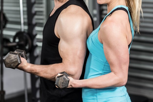 Pareja posando con mancuernas en el gimnasio de crossfit