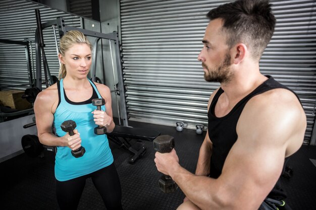 Pareja posando con mancuernas en el gimnasio