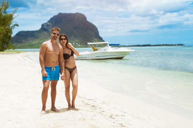 Pareja posando en la playa con yates y barcos