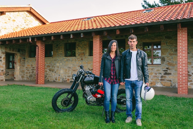 Pareja posando tomados de la mano y motocicleta personalizada