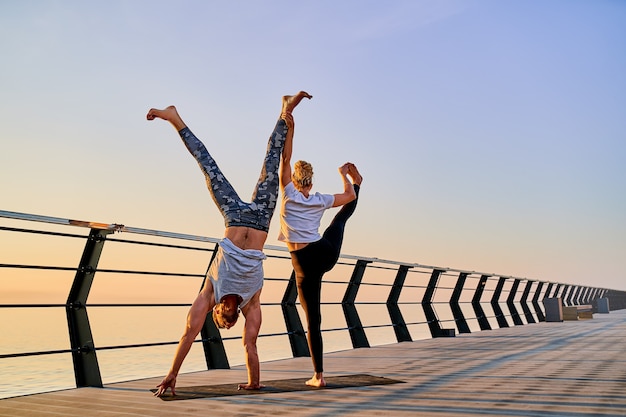 Pareja practicando yoga juntos en la naturaleza al aire libre ejercicios matutinos al amanecer.