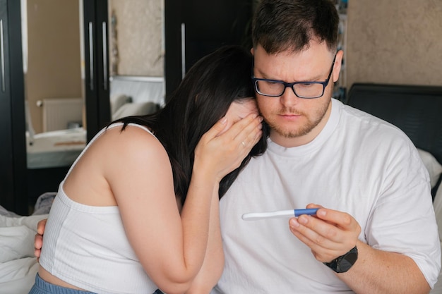 Pareja preocupada mirando una prueba de embarazo positiva no deseada