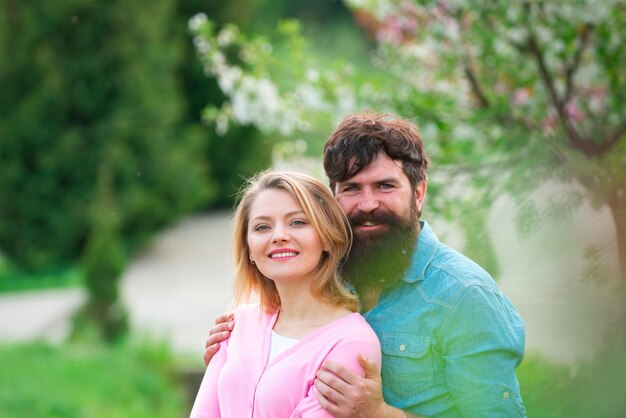 Pareja de primavera riendo y abrazándose amoroso hombre y mujer en un paseo en un parque floreciente de primavera