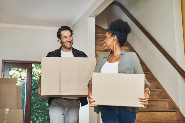 Pareja de propietarios que se mudan cargando cajas y desempacando en una nueva casa comprada como inversores inmobiliarios Sonrientes, felices y alegres hombres y mujeres interraciales compradores por primera vez y propietarios