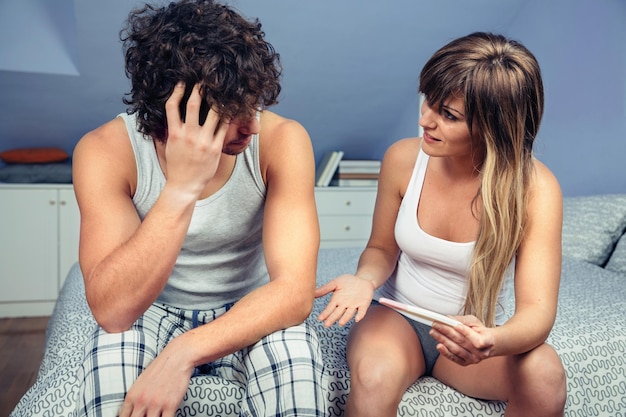 Foto pareja con prueba de embarazo en la cama en casa