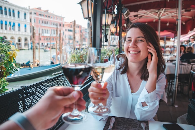 Pareja de punto de vista en primera persona en el café al aire libre bebiendo vino mujer sonriente gran canal de venecia