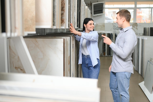 Una pareja que busca cerámica y azulejos para el piso de su nueva casa están eligiendo en la tienda de muebles