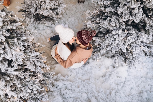 Foto una pareja se queda en la nieve en el bosque navideño.