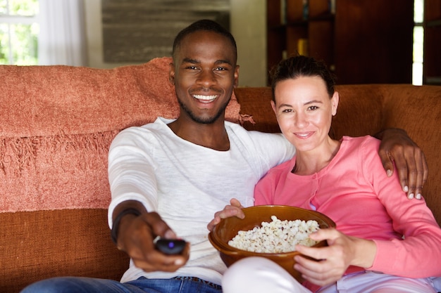 Pareja de raza mixta viendo una película en casa