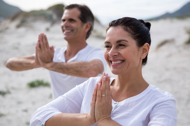 Foto pareja realizando yoga en la playa