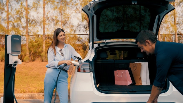 Foto una pareja recarga su coche eléctrico con la estación de carga de baterías eléctricas exalt