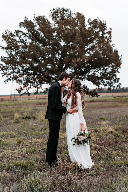 Una pareja de recién casados se besan mientras están de pie en el césped