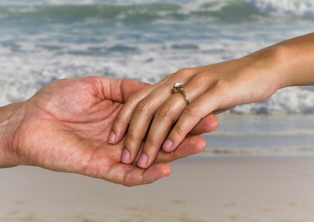 Pareja de recién casados cogidos de la mano en la playa