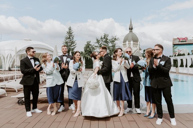 Pareja de recién casados, damas de honor y padrinos de boda divirtiéndose al aire libre