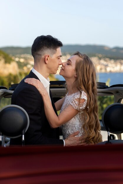 Una pareja de recién casados dentro de un auto pequeño