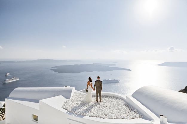 Una pareja de recién casados disfrutando de sus meses de luna de miel en grecia en la terraza sobre el mar