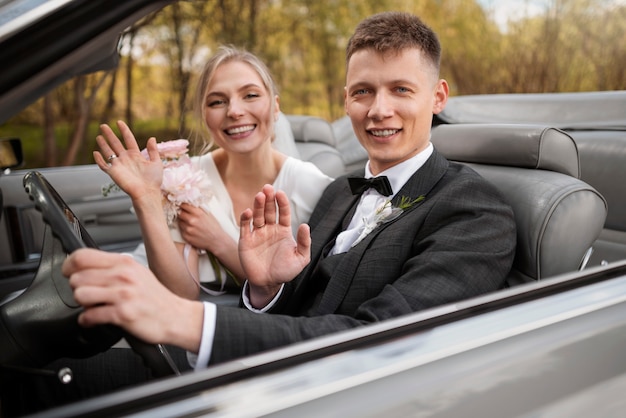 Foto pareja de recién casados con su coche